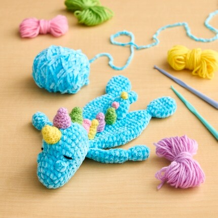 blue unicorn chenille crochet craft with yarn and hooks on table