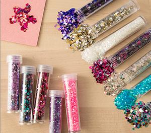 Various colors of glitter spilling out of plastic tubes on a table. 