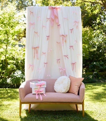 pink couch with background ivory curtains with pink bows throughout