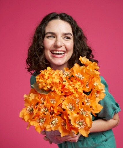 woman holding orange flowers with magenta background