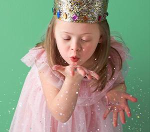 Little girl blowing glitter. She is in a princess like costume