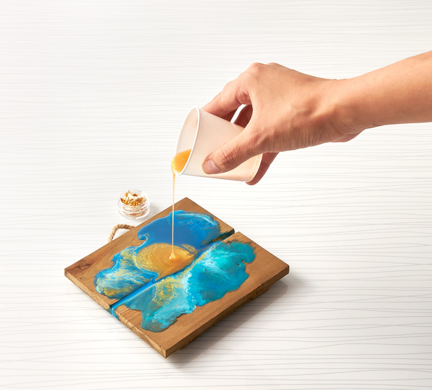 A hand pouring resin onto a coaster