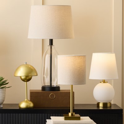 assorted cream and gold table lamps all lit placed on a table 