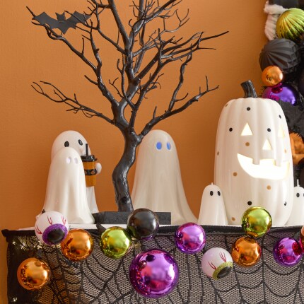 Halloween Tabletop Decorations in a mantel. White ghosts, ornament colorful garland and a tabletop black tree.