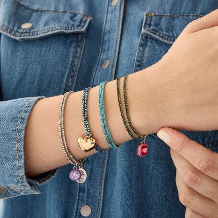 wrist with four seed bead bracelets with charms