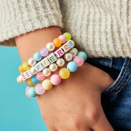 child's wrist with stacked bead pastel bracelets