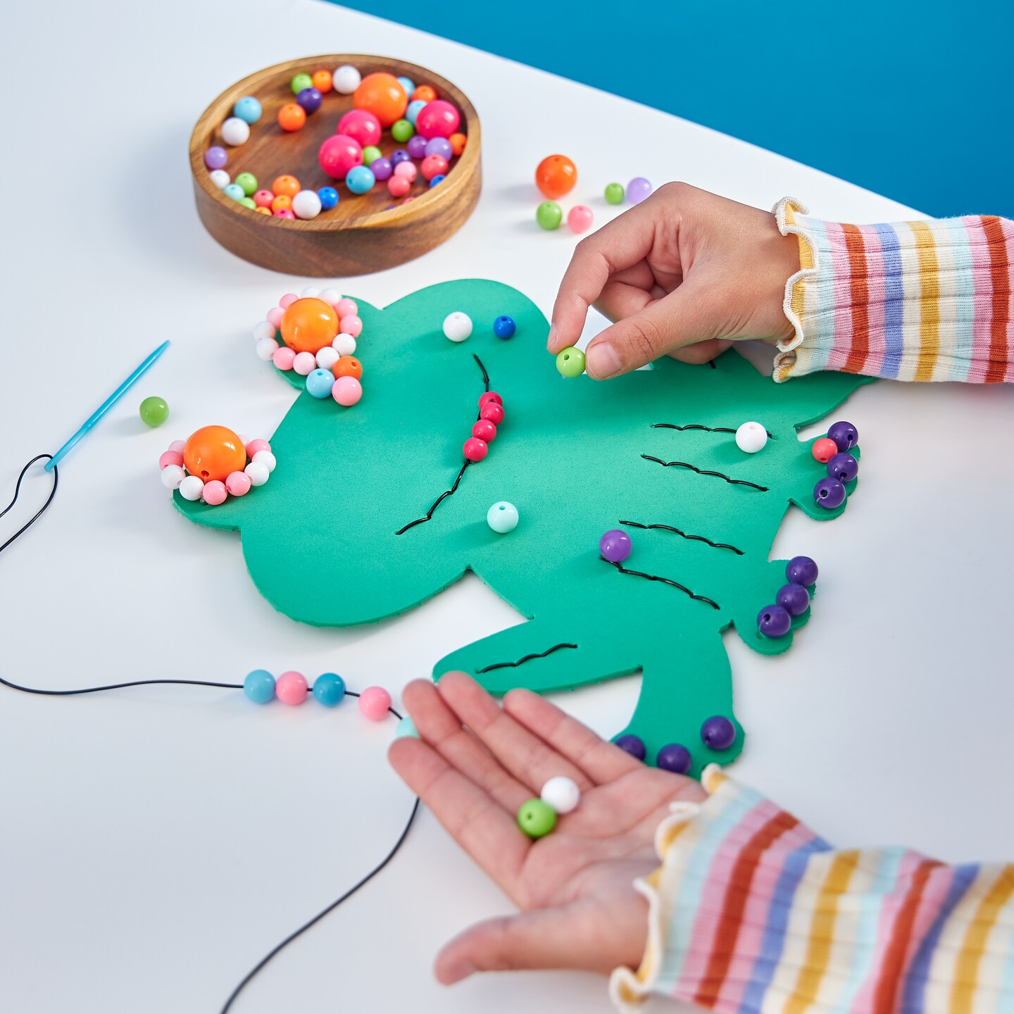 A child places pom poms on a paper frog