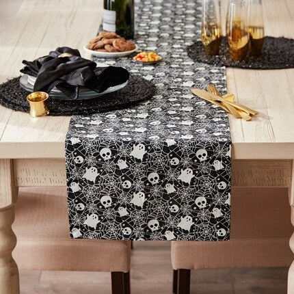 Halloween Party table linen with a ghost and skeleton pattern with a black background.