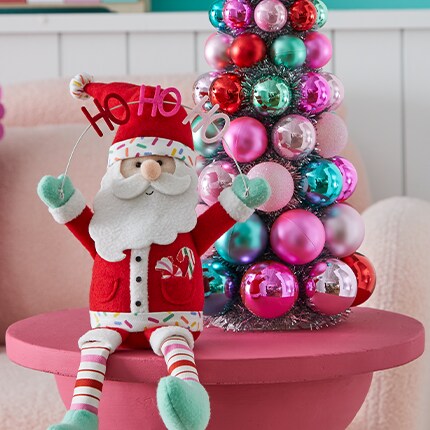 stuffed Santa on red table next to ornament tree decoration