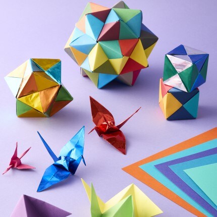 assorted colored origami cubes and red and blue origami birds on purple background