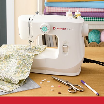 hands guiding blue fabric into Singer sewing machine