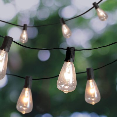 Lit Edison bulbs on black hardware strung on black string lights hanging in a backyard