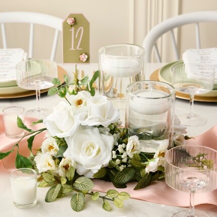 white floral centerpiece with floating candles and table number 12