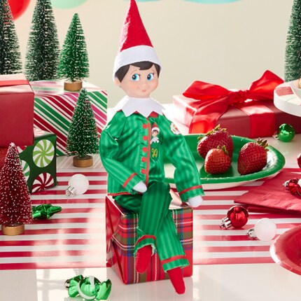 Elf on the shelf in striped green and white pajamas on a dinner table